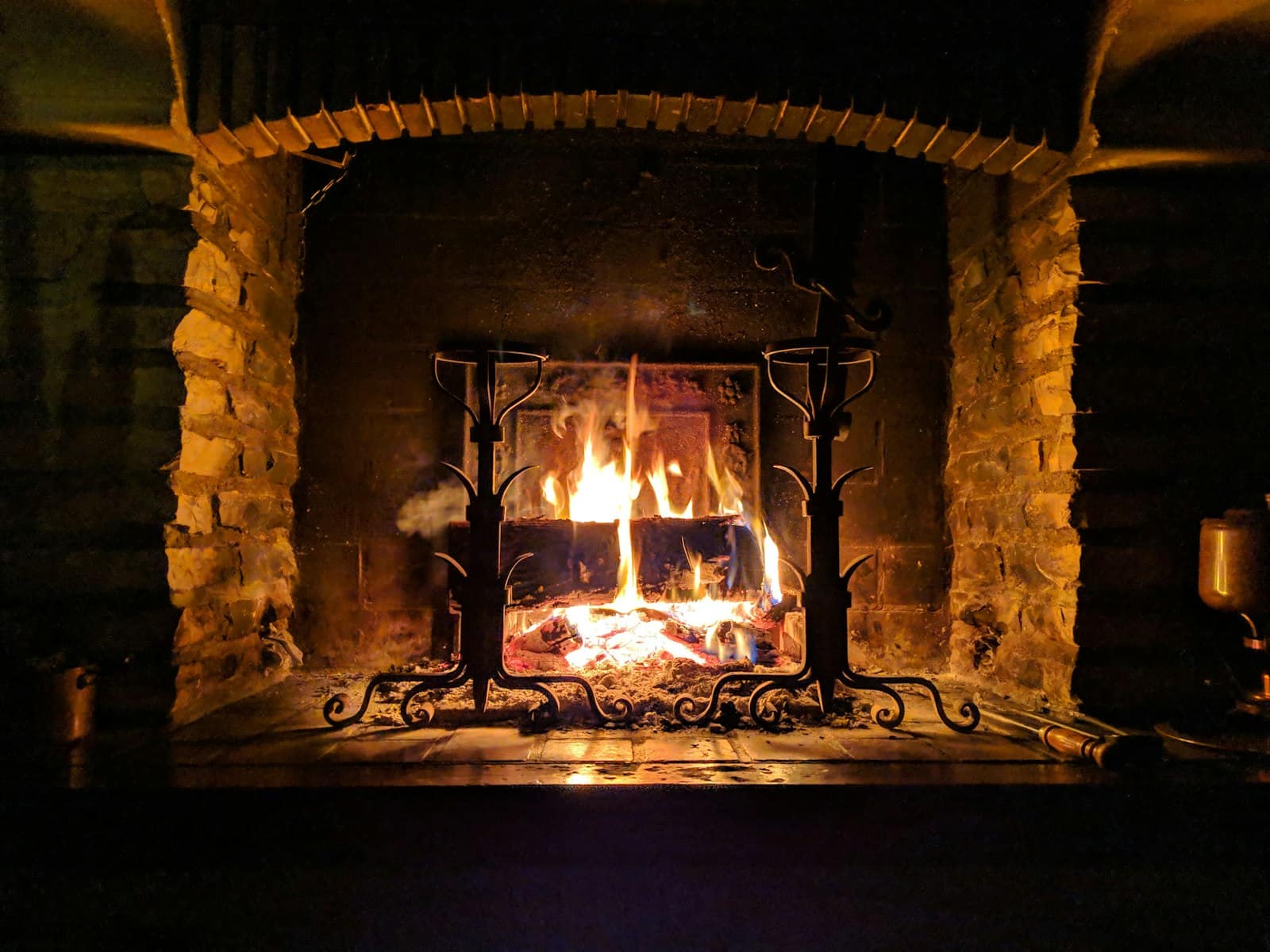 A wood fire burning on andirons in a brick hearth
