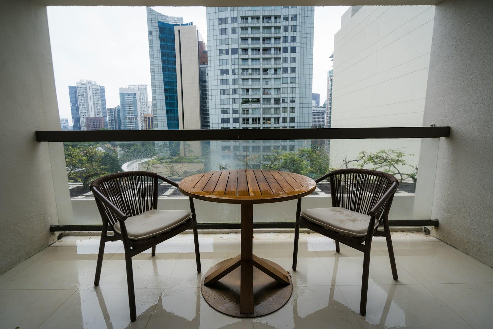 Two chairs and a round bistro table on a small high-rise balcony
