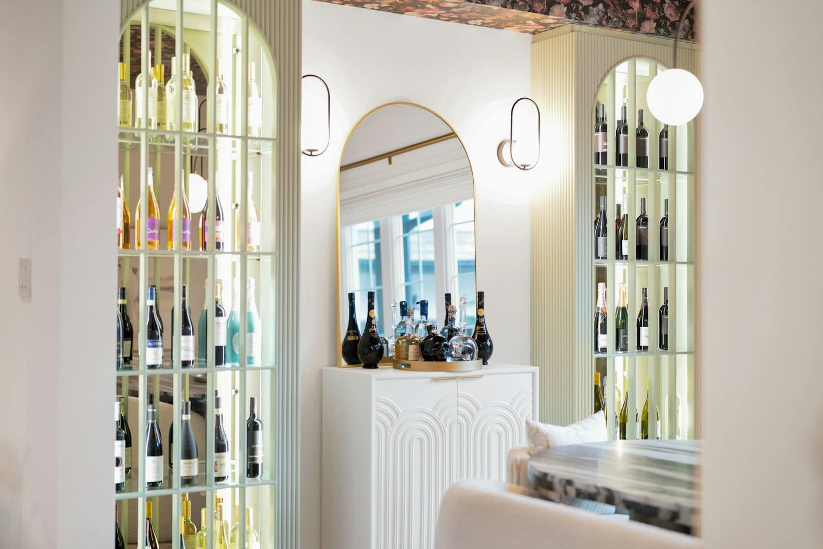 Arched glass-front wine cabinets flanking a white sideboard
