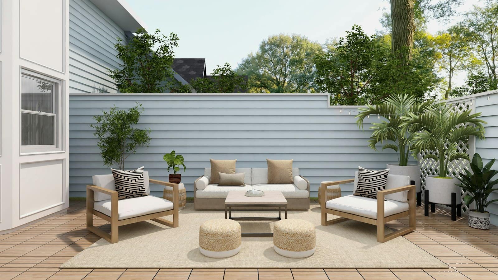 A patio with a teak-framed outdoor sofa, two armchairs, and woven poufs on a rug